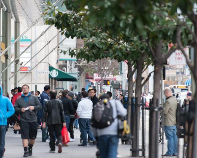 People walk along a busy sidewalk in SOMA