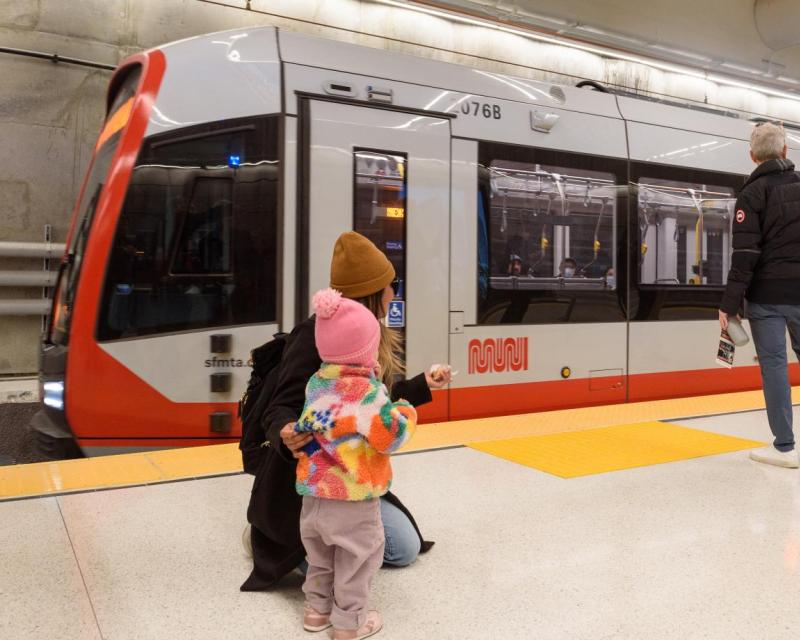 mother and child watch train arrive at muni metro platform