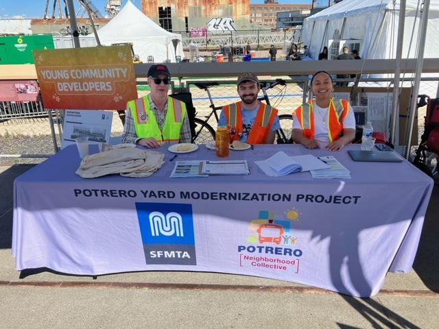 A group of people sitting at booth with a table wearing safety vests