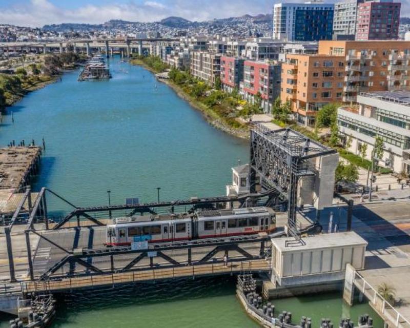 Photo by: Jim Maurer (CC BY-NC-ND 2.0). view of Islais Creek and the 4th street bridge with a Muni train passing by.